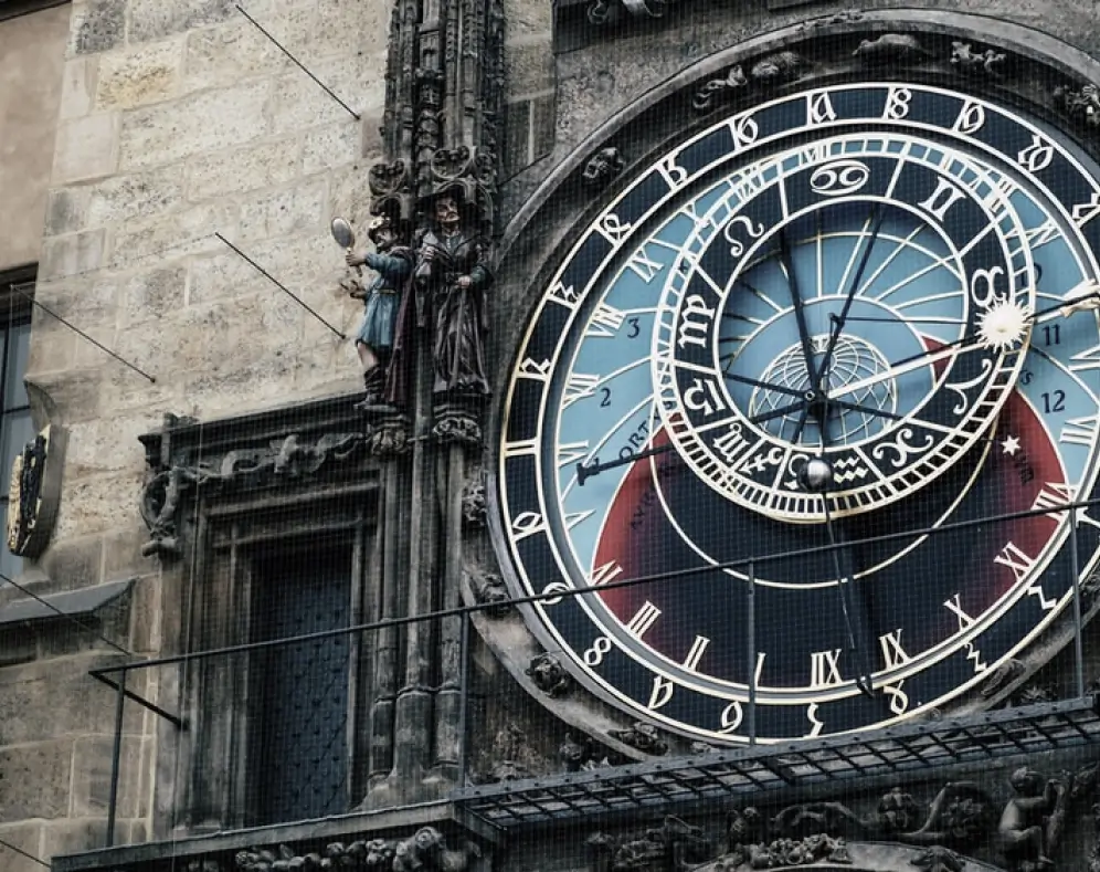Close-up of an ornate astronomical clock on a historic stone building.