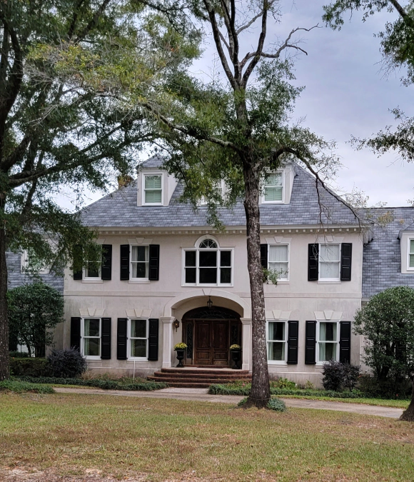 Large white colonial-style house with black shutters and a front porch.