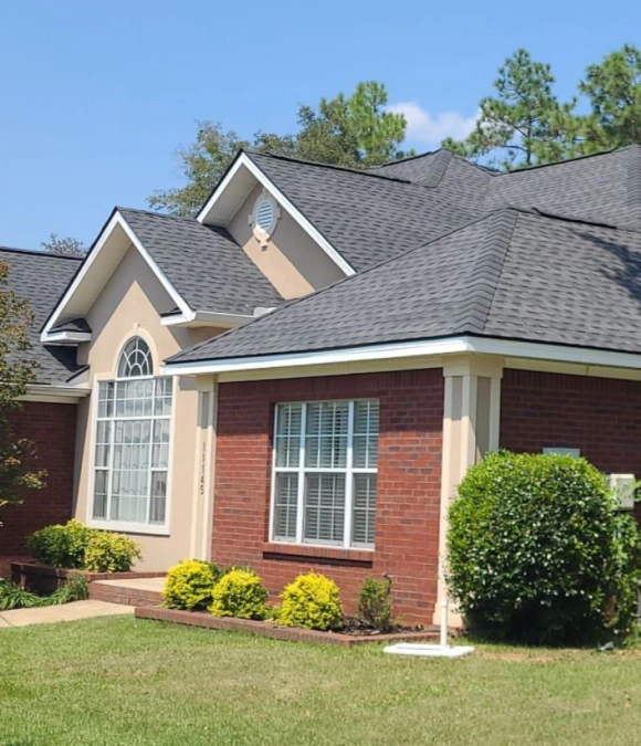Brick house with large windows and a well-kept lawn.